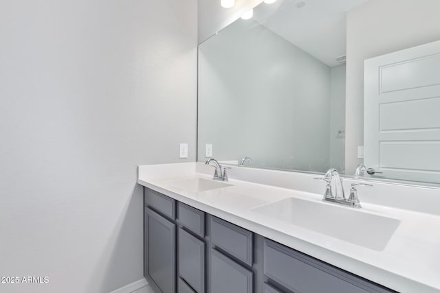 bathroom with a sink, baseboards, and double vanity