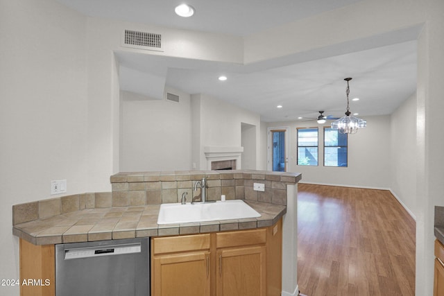 kitchen with sink, kitchen peninsula, wood-type flooring, decorative light fixtures, and dishwasher