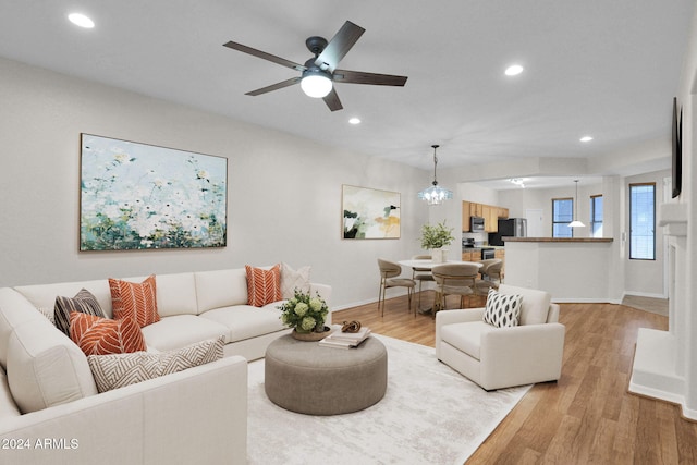 living room featuring light wood-type flooring and ceiling fan with notable chandelier