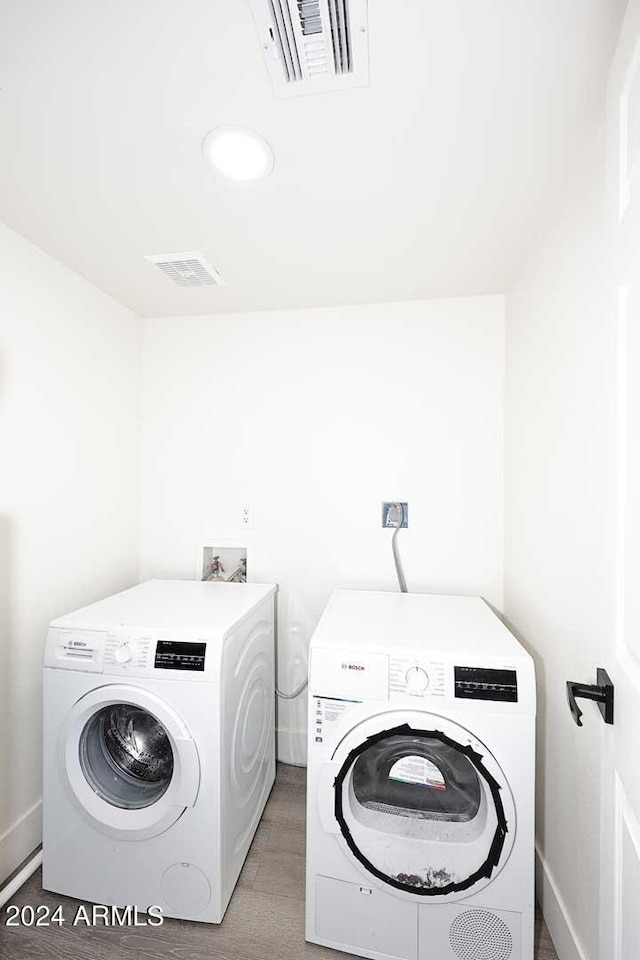 laundry area with independent washer and dryer, light wood-style floors, laundry area, and visible vents