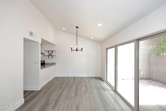 unfurnished dining area with a notable chandelier, vaulted ceiling, light wood-style flooring, baseboards, and visible vents