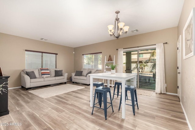 dining area with light wood-type flooring and an inviting chandelier