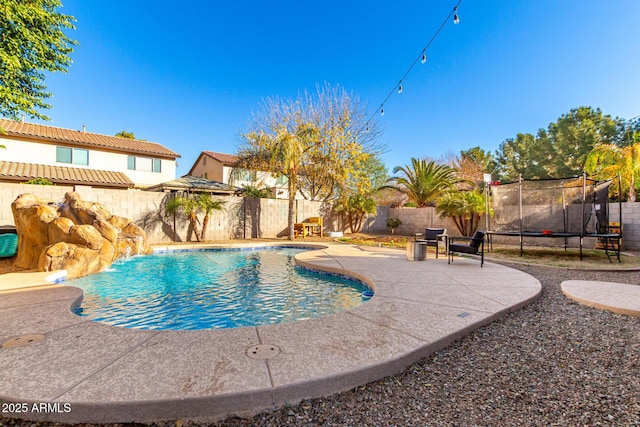 view of swimming pool with a trampoline, pool water feature, and a patio