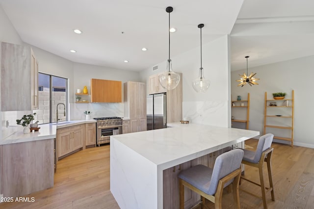 kitchen featuring pendant lighting, sink, appliances with stainless steel finishes, a kitchen bar, and kitchen peninsula