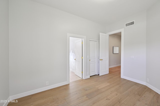 unfurnished bedroom featuring light hardwood / wood-style floors and ensuite bath