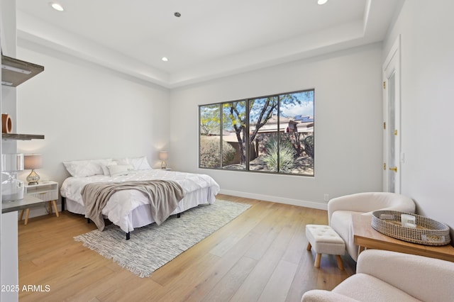 bedroom featuring light hardwood / wood-style floors and a raised ceiling