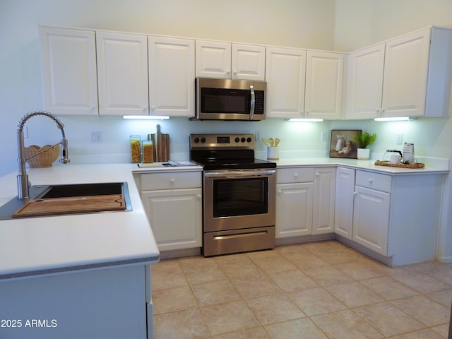kitchen featuring a sink, light tile patterned floors, stainless steel appliances, light countertops, and white cabinetry