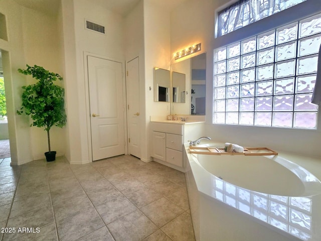 full bathroom featuring a bath, vanity, a high ceiling, tile patterned flooring, and visible vents