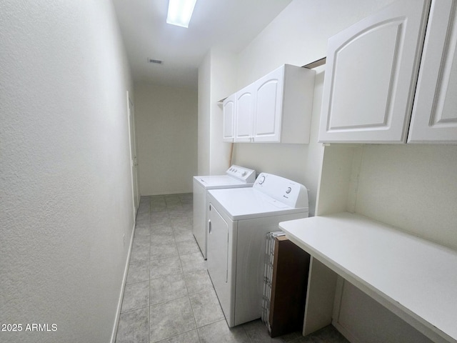 laundry area featuring a textured wall, visible vents, light tile patterned floors, washing machine and clothes dryer, and cabinet space