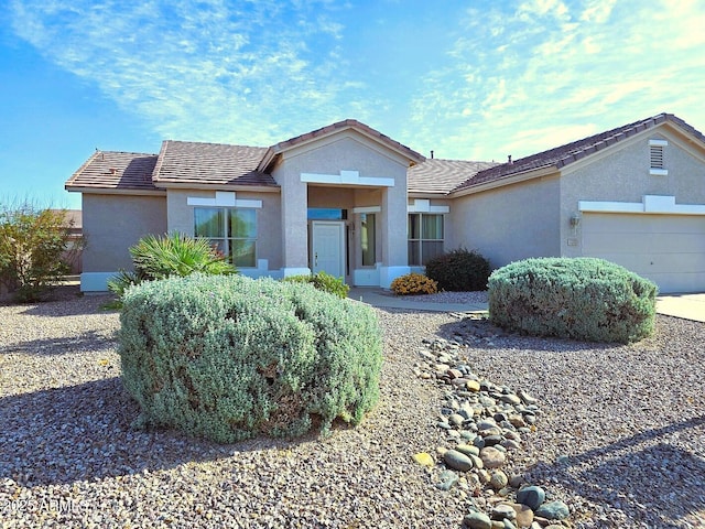 ranch-style house with a garage, a tile roof, and stucco siding
