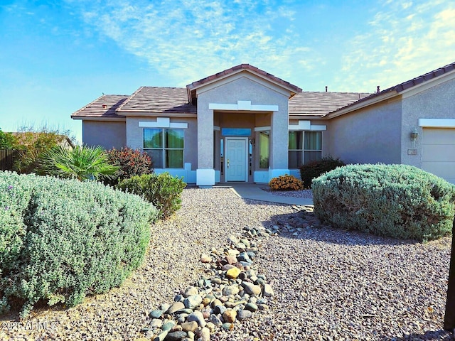 ranch-style home featuring stucco siding, an attached garage, and a tiled roof