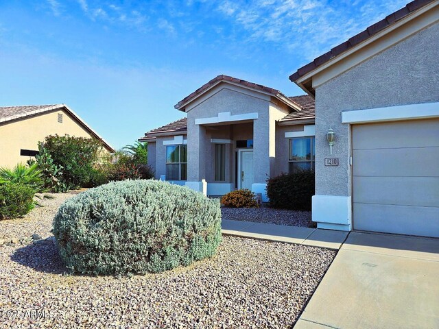 view of front of house featuring a garage, a tile roof, and stucco siding