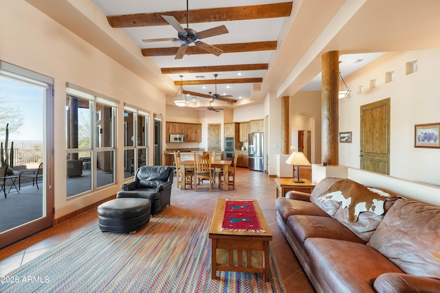 living area with light tile patterned floors, ceiling fan, beamed ceiling, and a towering ceiling