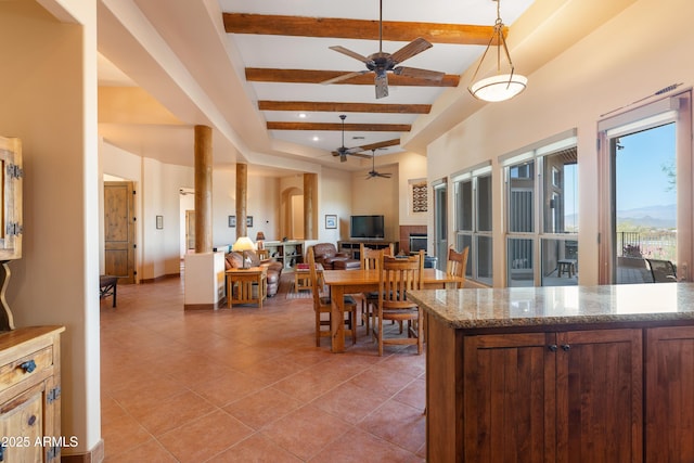 kitchen with light tile patterned floors, a ceiling fan, open floor plan, decorative light fixtures, and beam ceiling