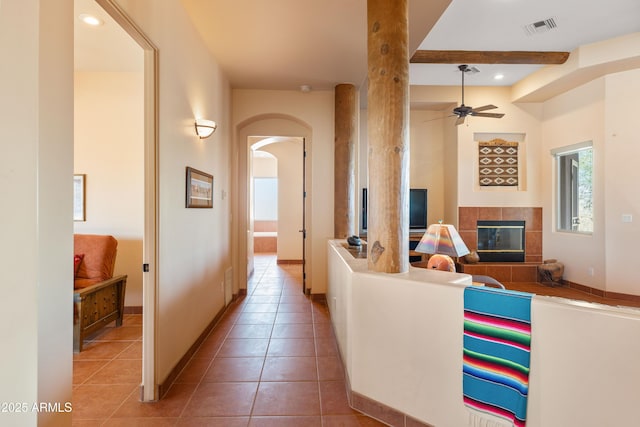 hallway with light tile patterned floors, baseboards, visible vents, arched walkways, and recessed lighting