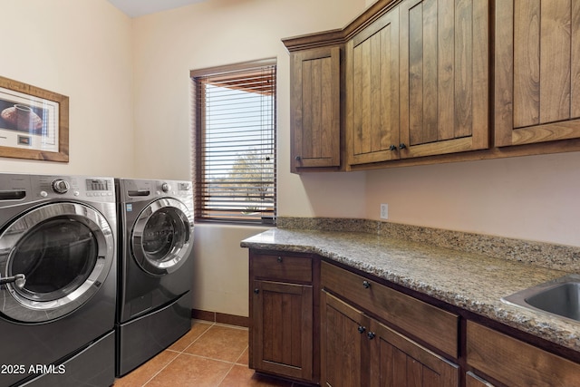 washroom with washing machine and dryer, cabinet space, baseboards, and light tile patterned floors