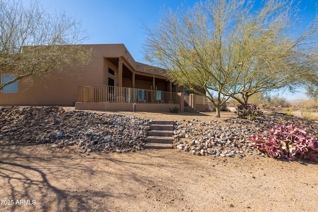 rear view of house featuring covered porch and stucco siding