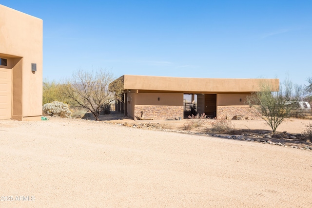 view of front of house with a garage, stone siding, and stucco siding