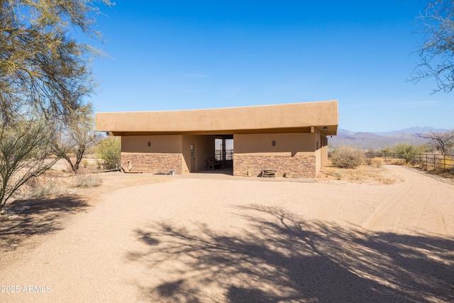 adobe home featuring stone siding, driveway, a mountain view, and stucco siding