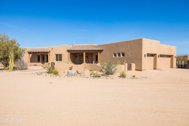 southwest-style home featuring driveway, a tile roof, and stucco siding