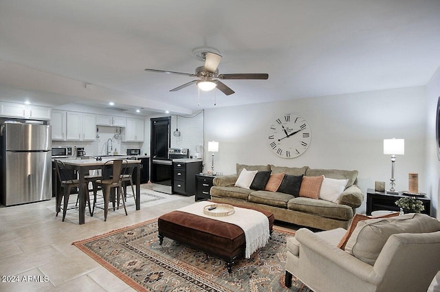 tiled living room with ceiling fan and sink