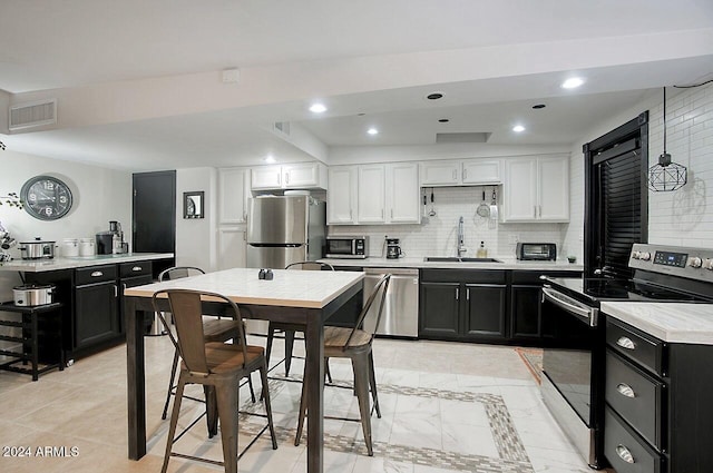 kitchen featuring decorative backsplash, sink, white cabinets, and stainless steel appliances