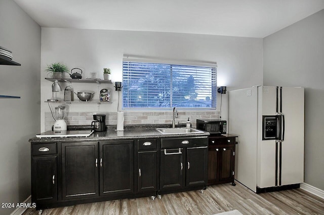 bar featuring tasteful backsplash, white fridge with ice dispenser, light hardwood / wood-style floors, and sink