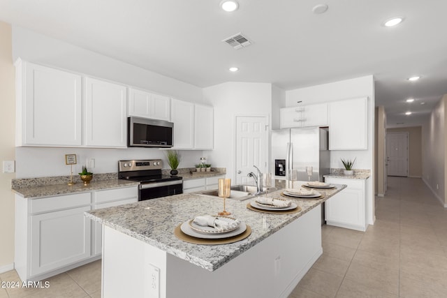 kitchen featuring light stone countertops, white cabinetry, sink, stainless steel appliances, and an island with sink