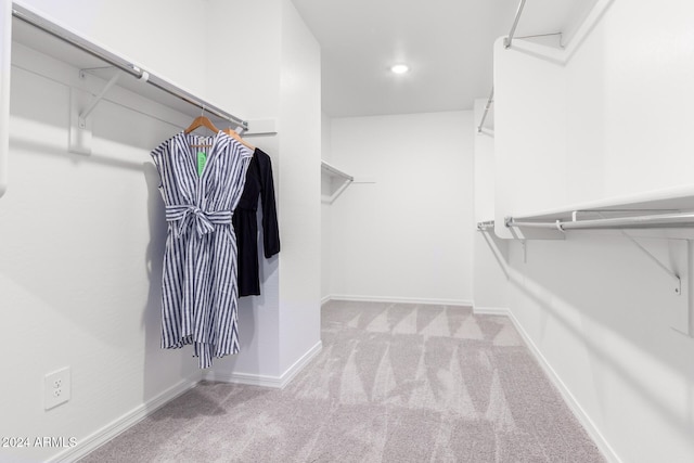 walk in closet with light carpet