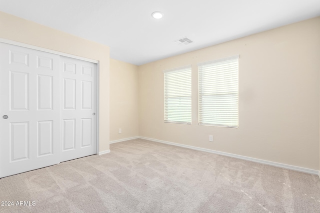 unfurnished bedroom with light carpet and a closet