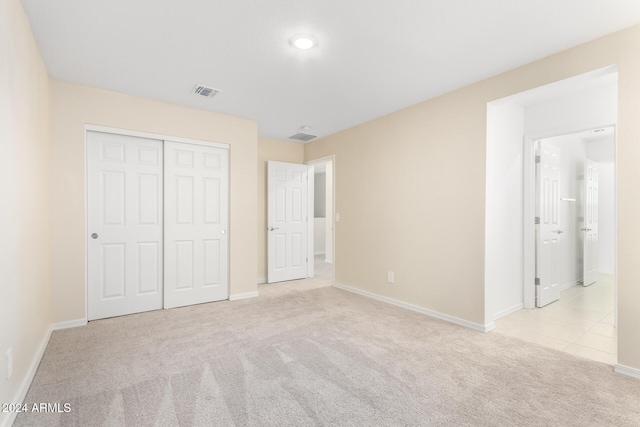 unfurnished bedroom with a closet and light colored carpet