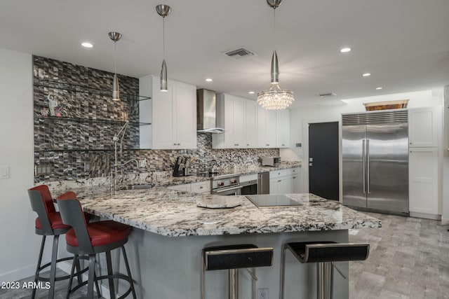 kitchen featuring white cabinetry, wall chimney exhaust hood, pendant lighting, and stainless steel built in refrigerator