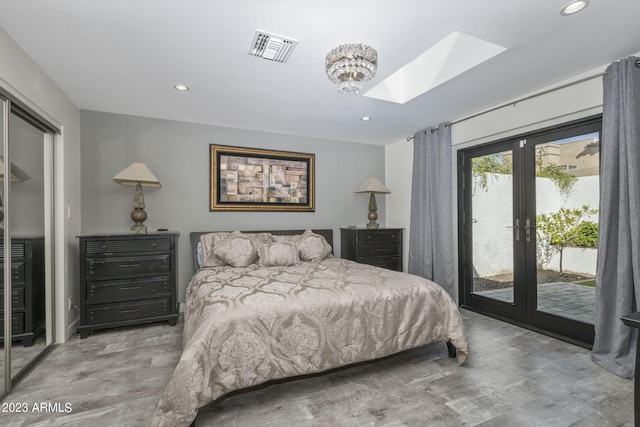 bedroom with access to outside, a skylight, wood-type flooring, french doors, and a closet