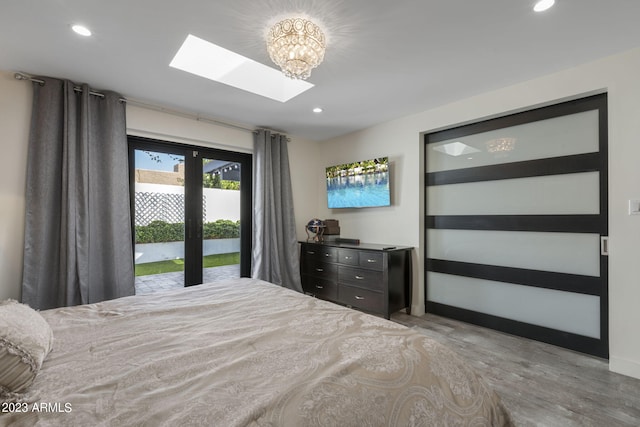 bedroom with access to outside, a skylight, and light wood-type flooring