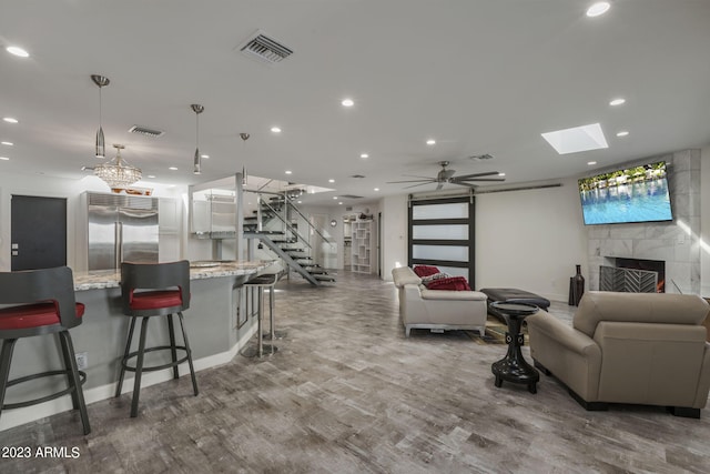 living room featuring a tiled fireplace, hardwood / wood-style flooring, and ceiling fan