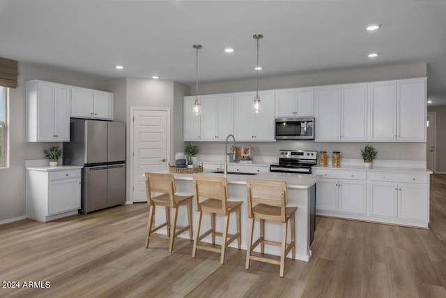 3035 W Thurman Dr, Laveen, AZ 85339 - kitchen with light countertops, light wood-style flooring, white cabinets, appliances with stainless steel finishes, and an island with sink