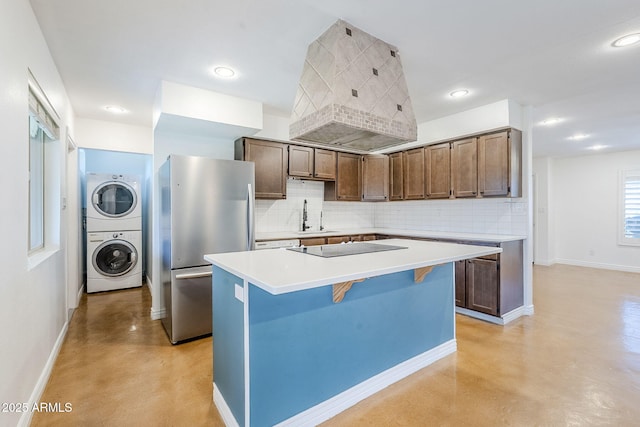 8713 E Sage Dr, Scottsdale, AZ 85250 - kitchen featuring freestanding refrigerator, stacked washing machine and dryer, a sink, concrete flooring, and tasteful backsplash