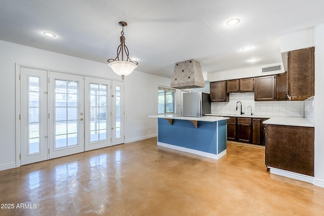 8713 E Sage Dr, Scottsdale, AZ 85250 - kitchen with freestanding refrigerator, baseboards, finished concrete floors, dark brown cabinets, and tasteful backsplash
