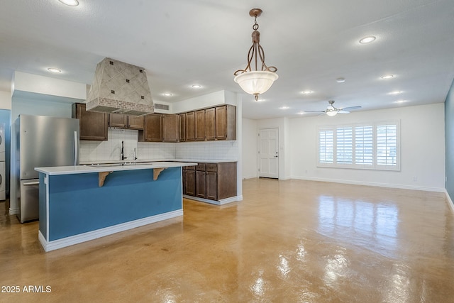 8713 E Sage Dr, Scottsdale, AZ 85250 - kitchen with freestanding refrigerator, finished concrete floors, tasteful backsplash, a breakfast bar, and stacked washing machine and dryer