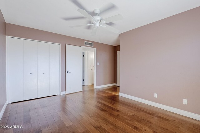 8713 E Sage Dr, Scottsdale, AZ 85250 - unfurnished bedroom with baseboards, wood finished floors, a closet, and a ceiling fan
