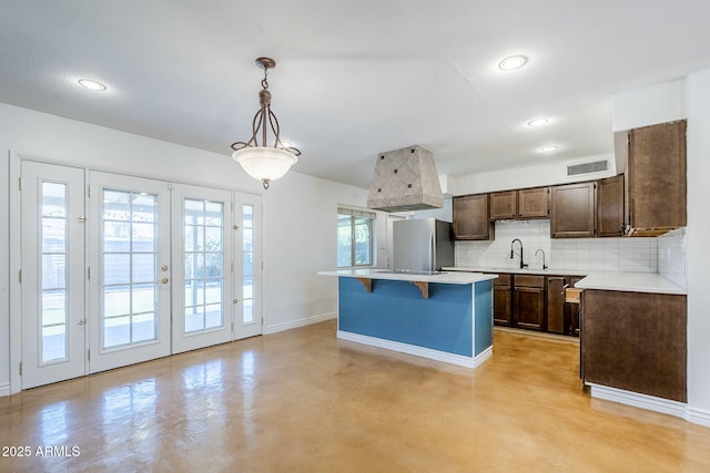 8713 E Sage Dr, Scottsdale, AZ 85250 - kitchen featuring freestanding refrigerator, baseboards, backsplash, light countertops, and a kitchen breakfast bar