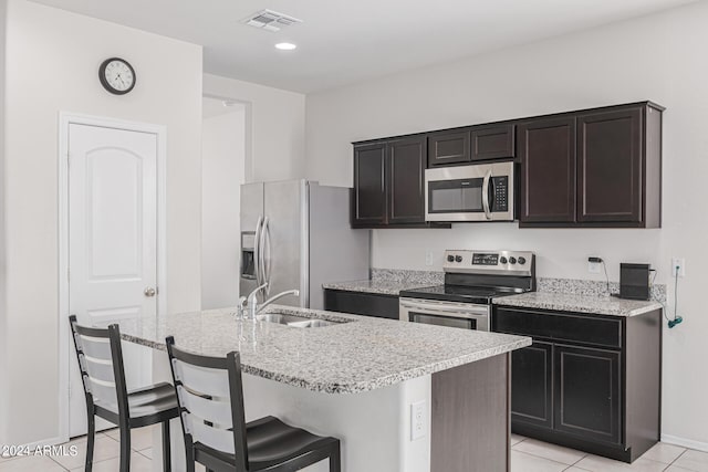 kitchen featuring a kitchen island with sink, a breakfast bar, sink, stainless steel appliances, and light tile patterned floors