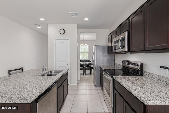 kitchen featuring sink, a notable chandelier, appliances with stainless steel finishes, a center island with sink, and light tile patterned floors