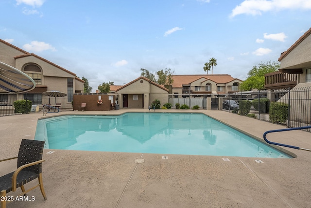 community pool featuring fence, a patio area, and a residential view
