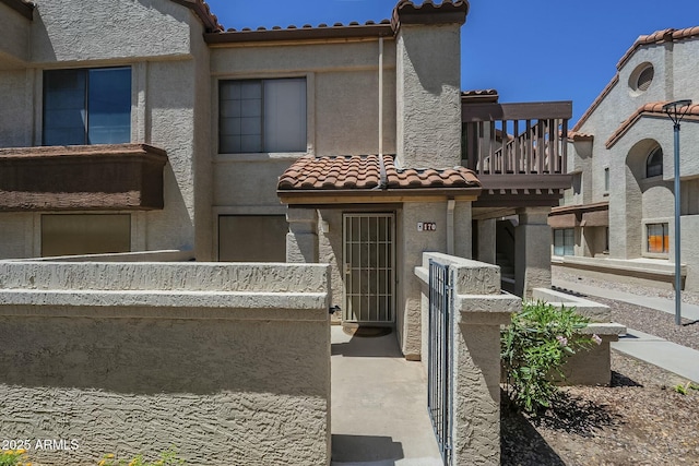 view of front facade with a tiled roof, a balcony, and stucco siding