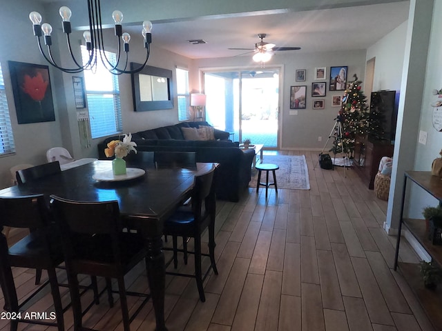 dining area featuring wood-type flooring and ceiling fan with notable chandelier