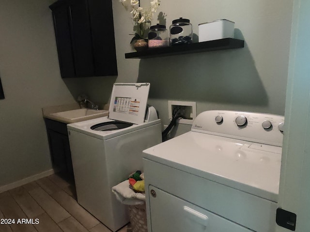 laundry area with sink, hardwood / wood-style flooring, washing machine and dryer, and cabinets