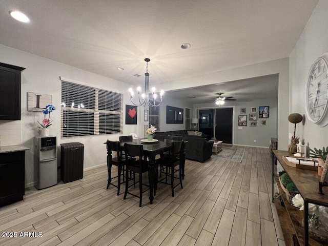 dining room with ceiling fan with notable chandelier and light hardwood / wood-style floors