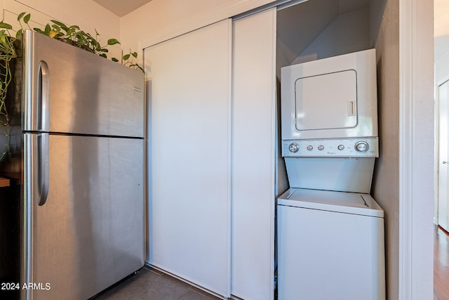 washroom with stacked washer and dryer and dark tile patterned floors