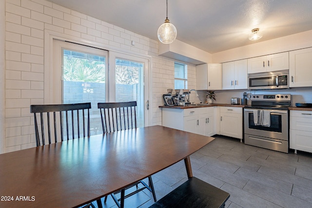 kitchen featuring appliances with stainless steel finishes, decorative backsplash, decorative light fixtures, and white cabinets